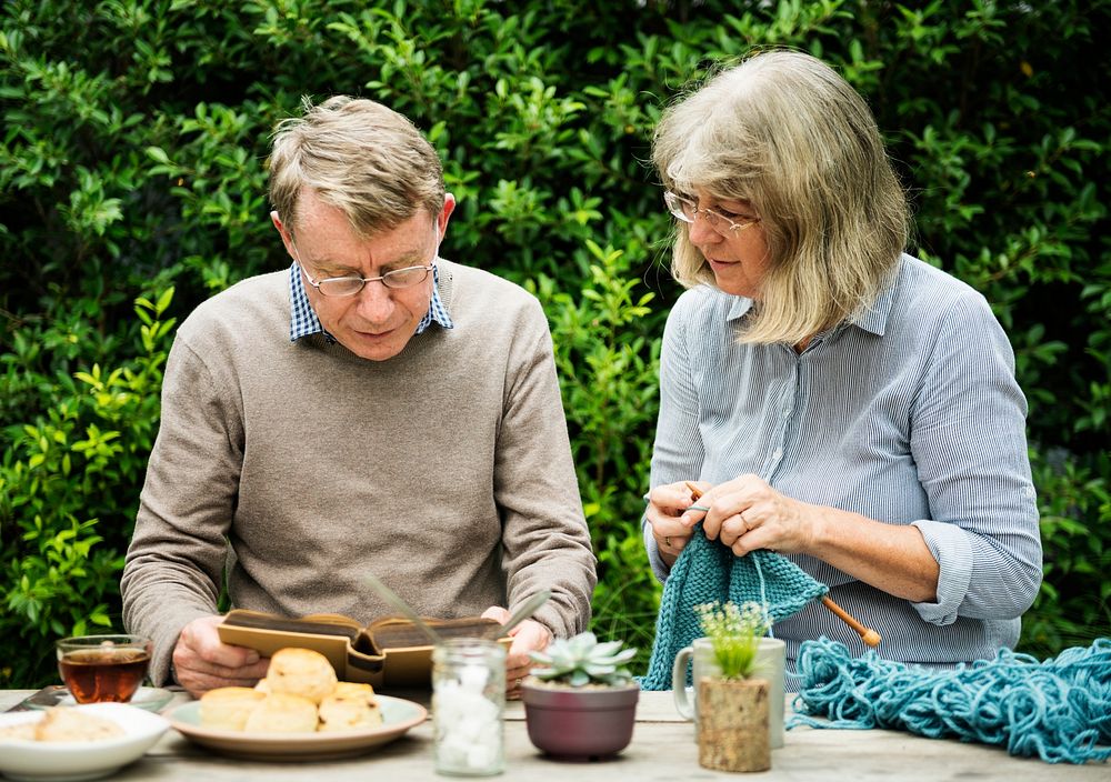 Elderly couple enjoying tea and knitting outdoors