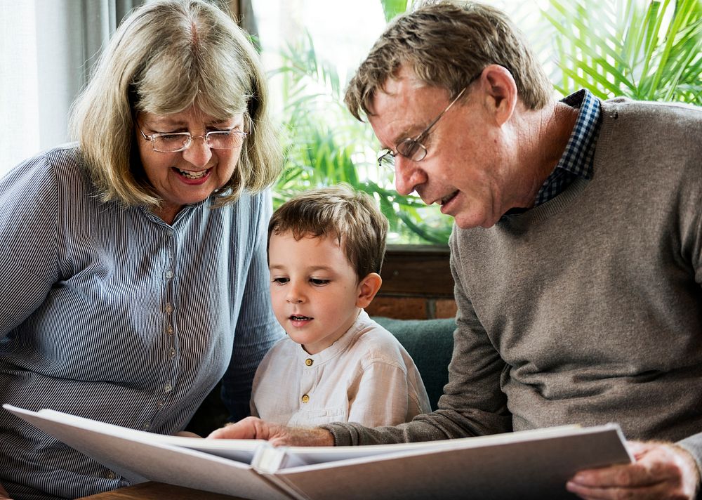 Little boy looking at a picture album with his grandparents