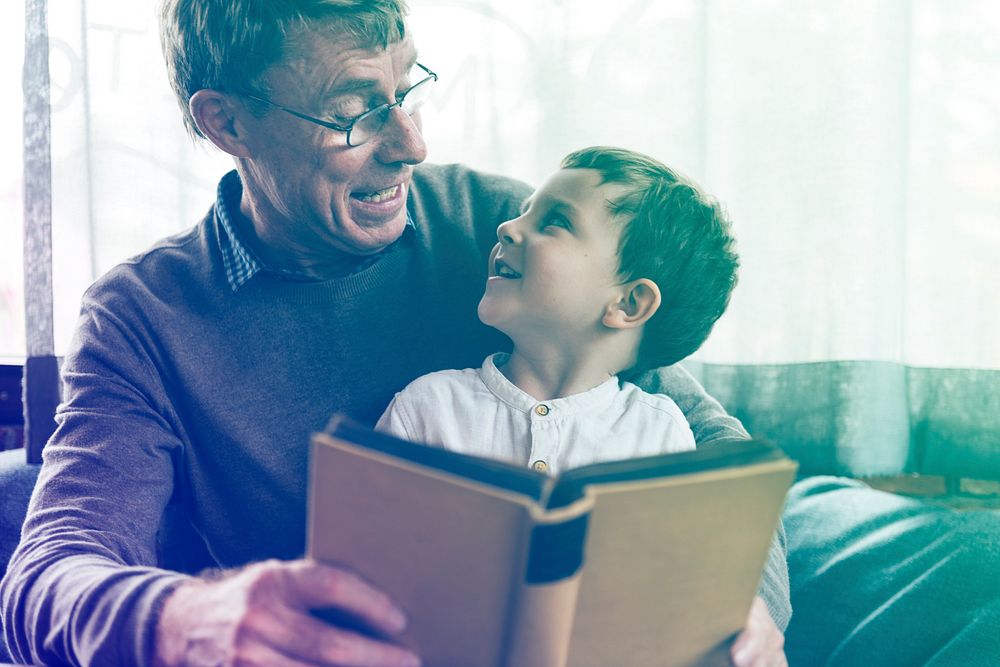 Grandfather and little cute grandson reading book together
