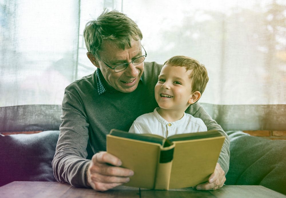 Grandfather and little cute grandson reading book together