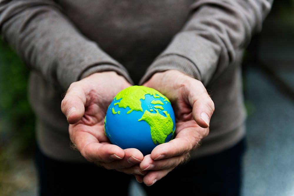 Hands holding a clay globe planet Earth