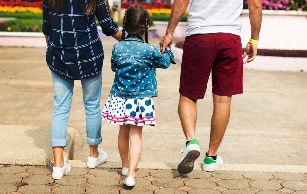 Rear view of family holding hands together while walking