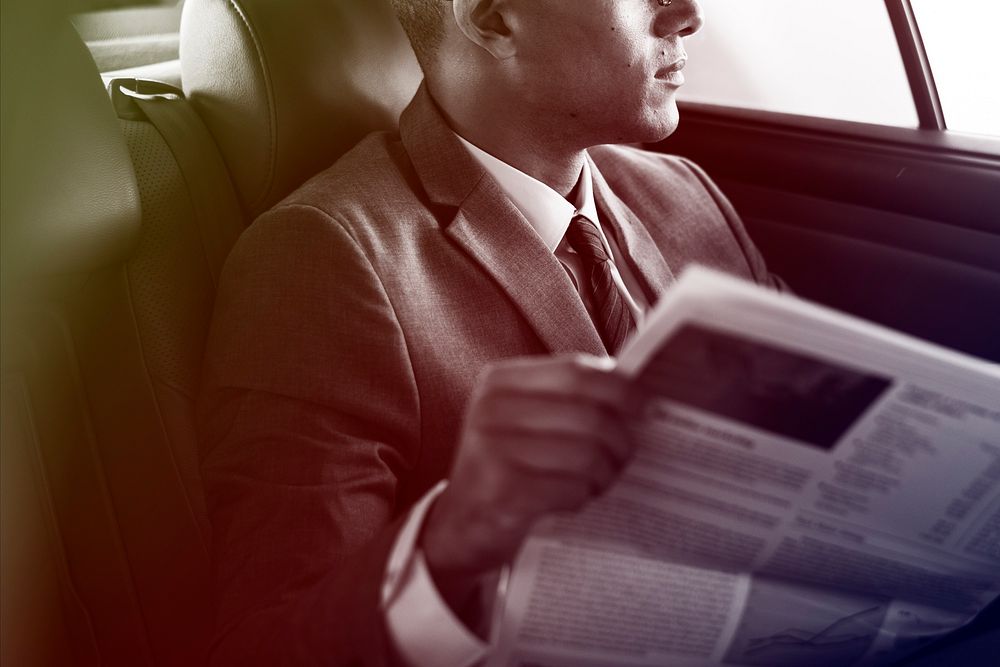 Businessman reading newspaper on the car