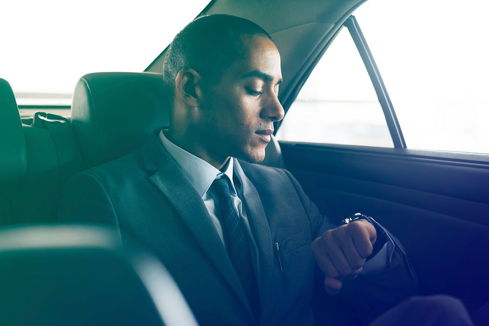 Businessman sitting on the back seat looking watch