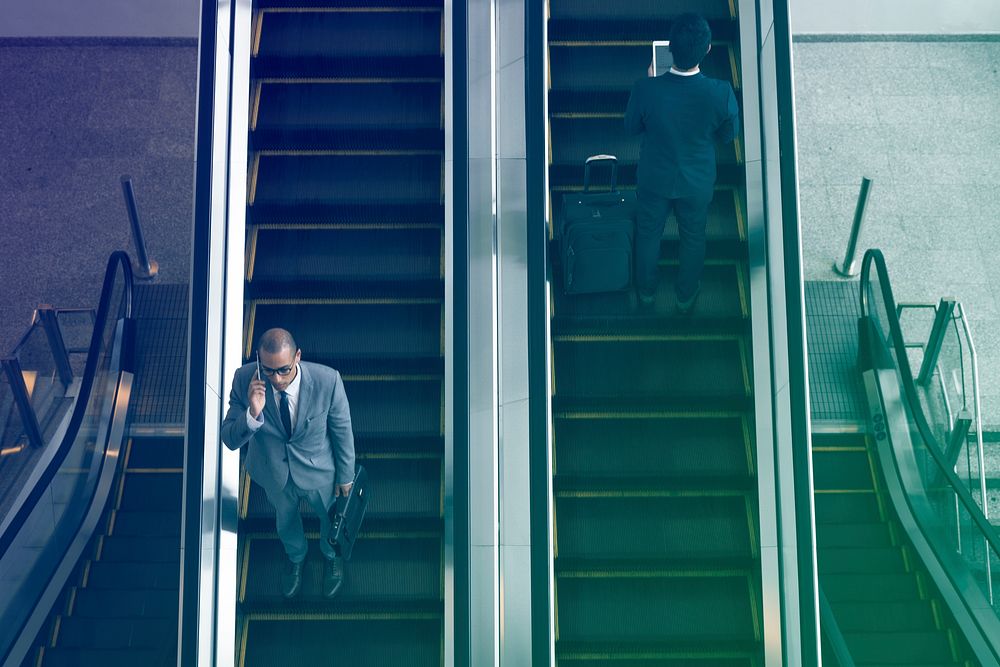Business people using escalator and talking phone