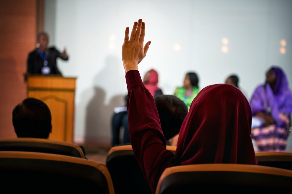 A Person Raising Her Hand to Ask a Question in a Panel Discussion 
