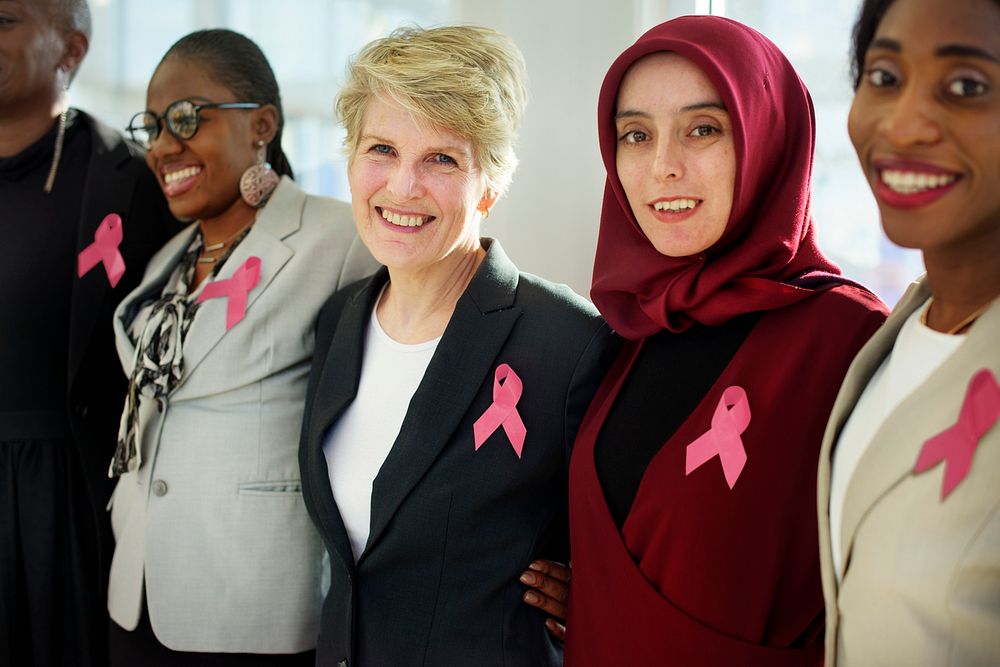 Group of Business Women Smiling and Wearing Pink Ribbons for Breast Cancer Awareness