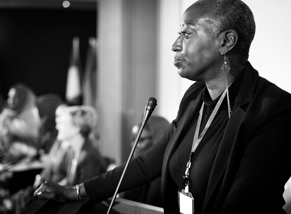 A Middle Age African Descent Woman Speaking into a Microphone