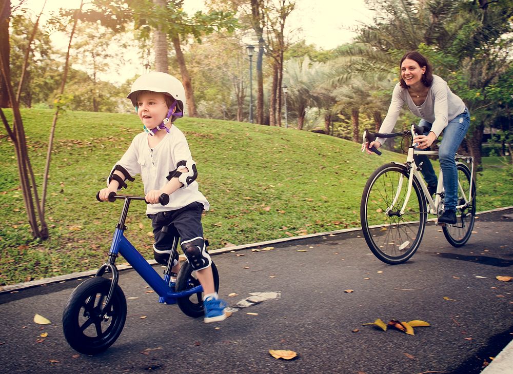 Little boy and his mother riding bicycle in the park