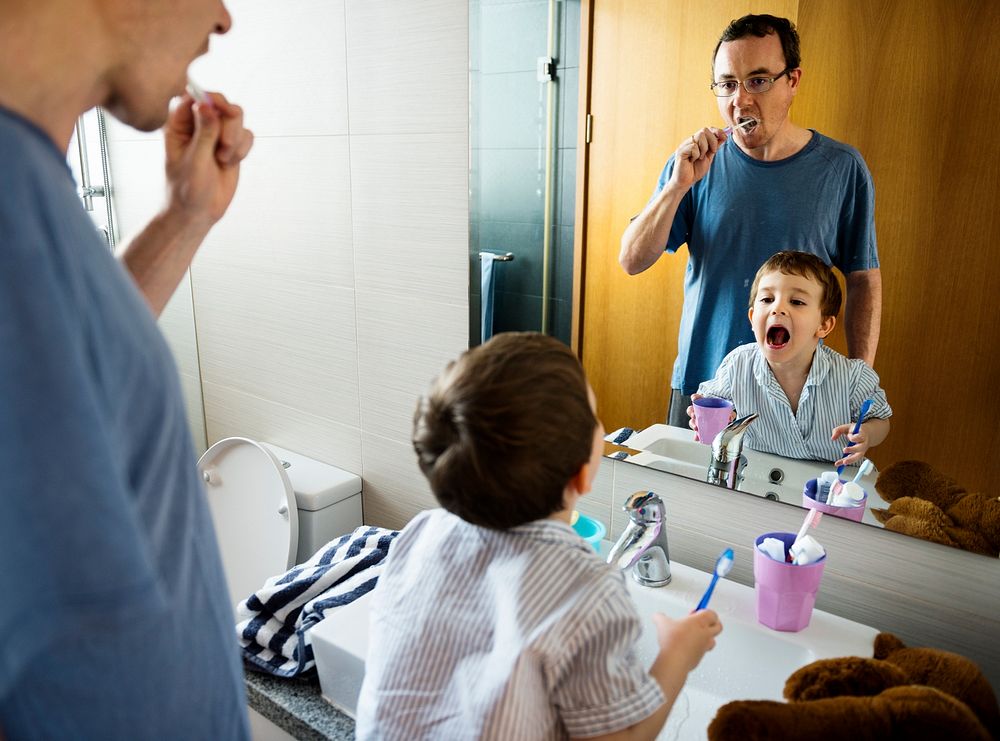 Dad and son brushing their teeth together in the morning