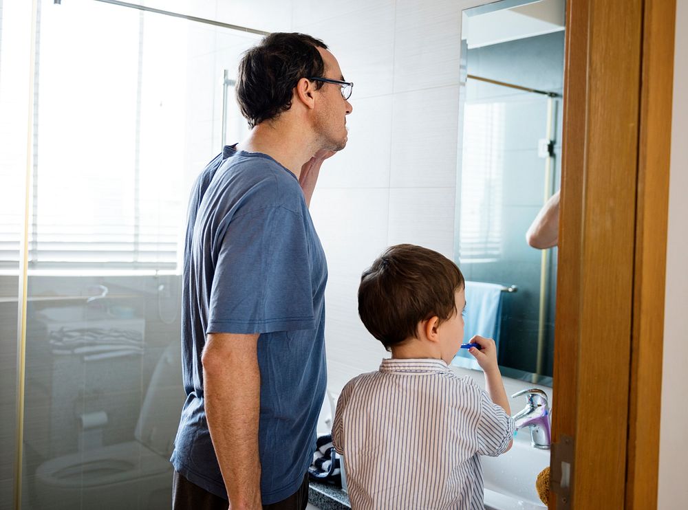 Father teaching son how to brush his teeth