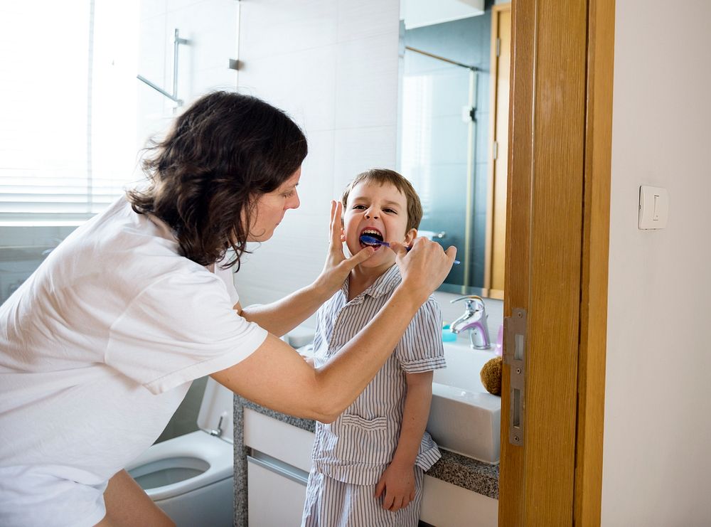 Mother helping son to brush his teeth