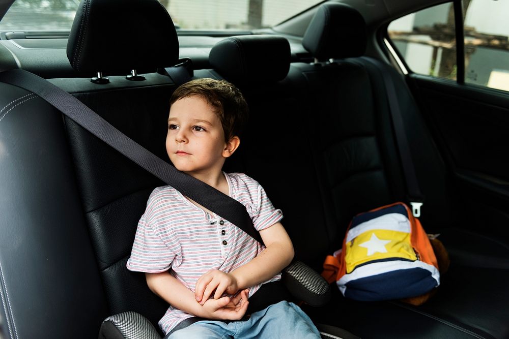 Little boy sitting in the car with seatbelt on for safety