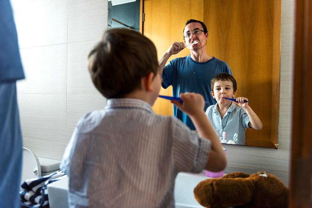 Father teaching son how to brush his teeth