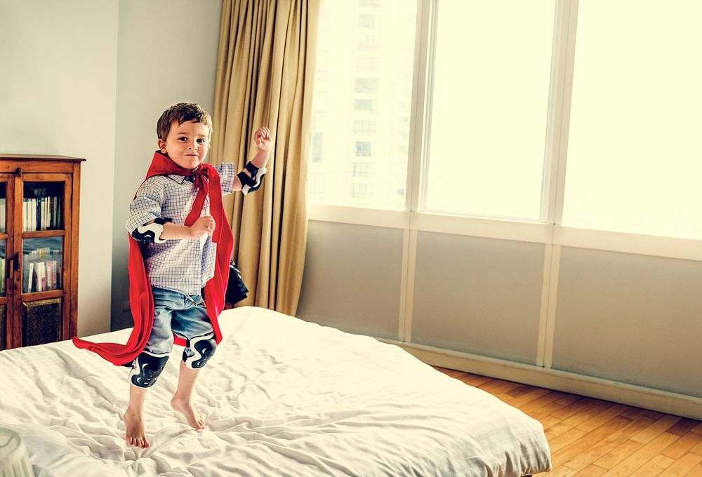 Boy with a superhero custome in a bedroom.