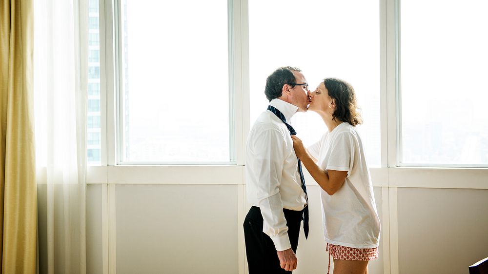 Woman kissing husband while dressing up