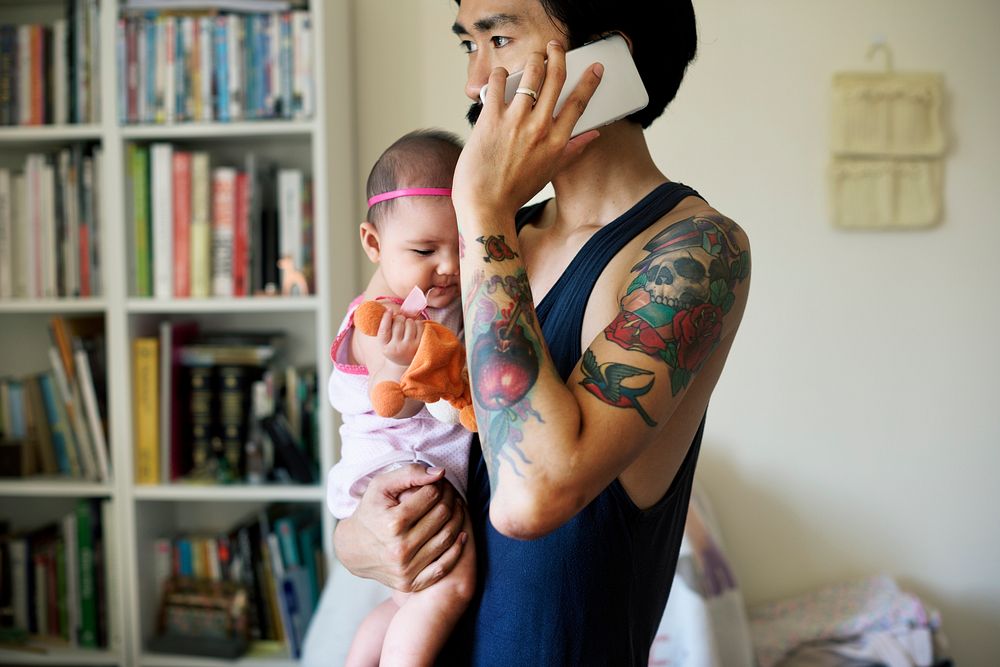 Daddy Talking Mobile Phone While Carrying His Baby