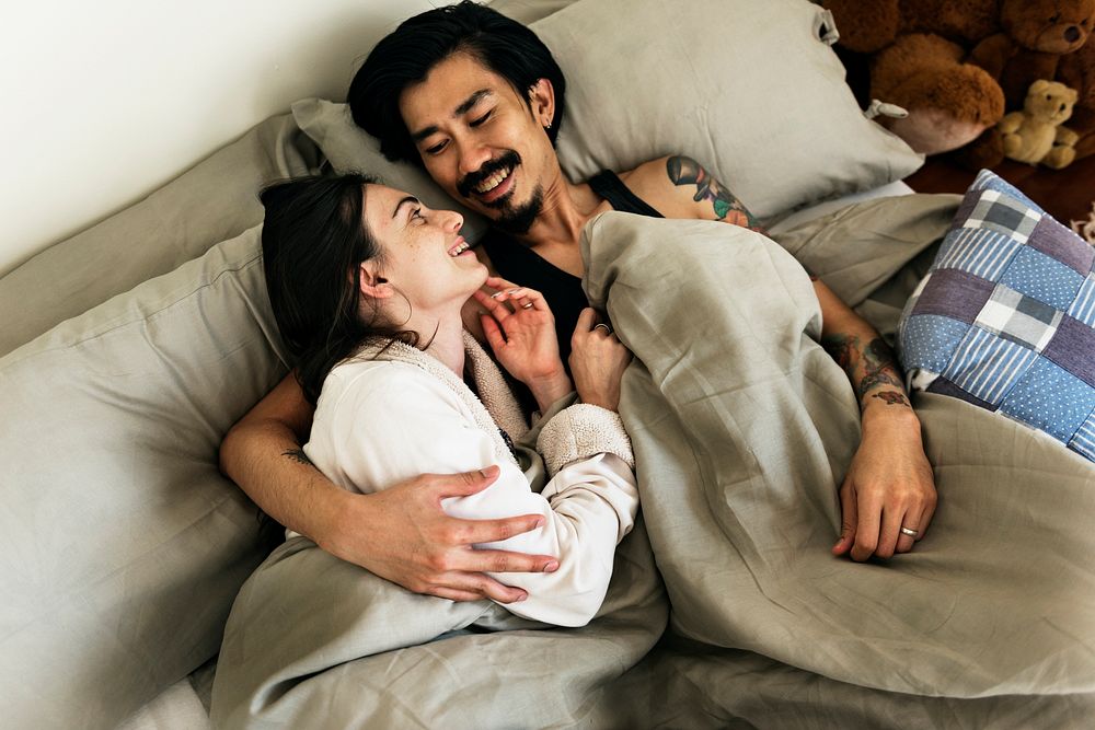 Couple is on a bed hugging.