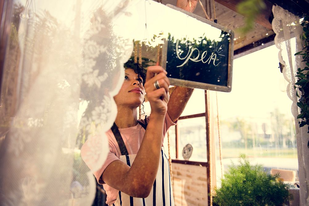 Woman Hanging Open Sign by the Glass Window