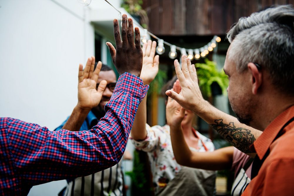 Group of diverse people with hands raised teamwork