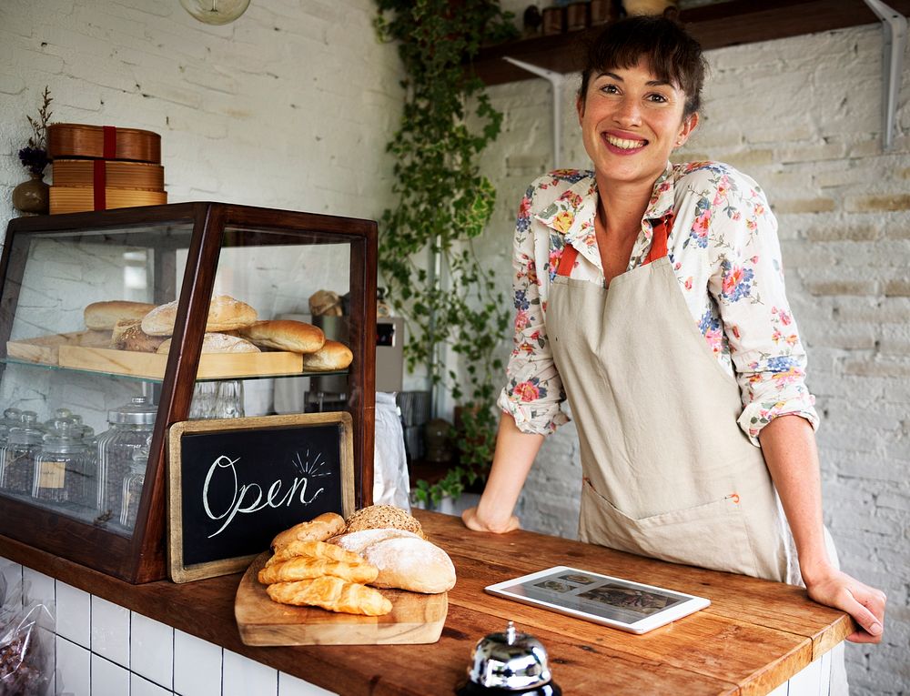 Smiling woman at the wooden bake house counter with digital tablet