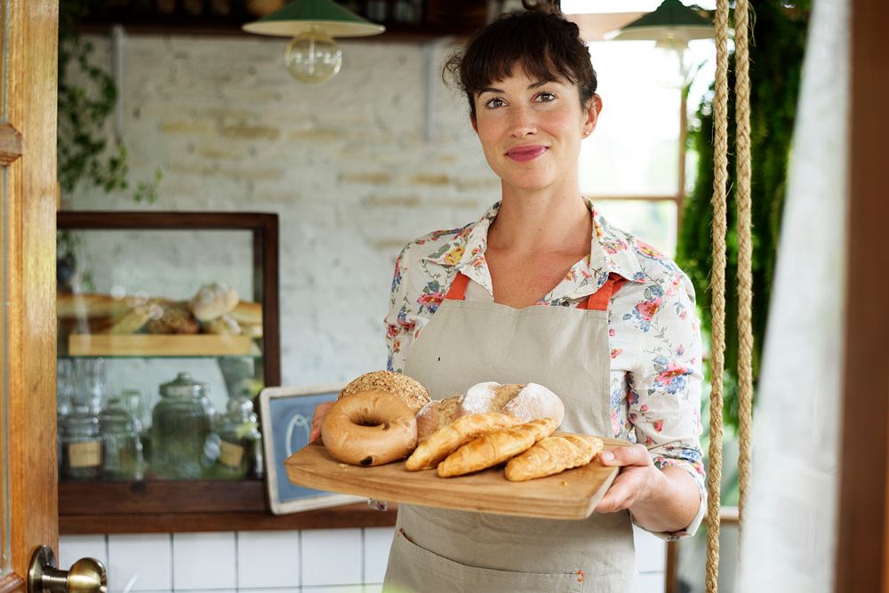 Woman holding fresh baked bread on wooden tray