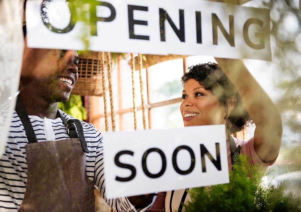 Black Couple Showing Opening Soon Paper Sign
