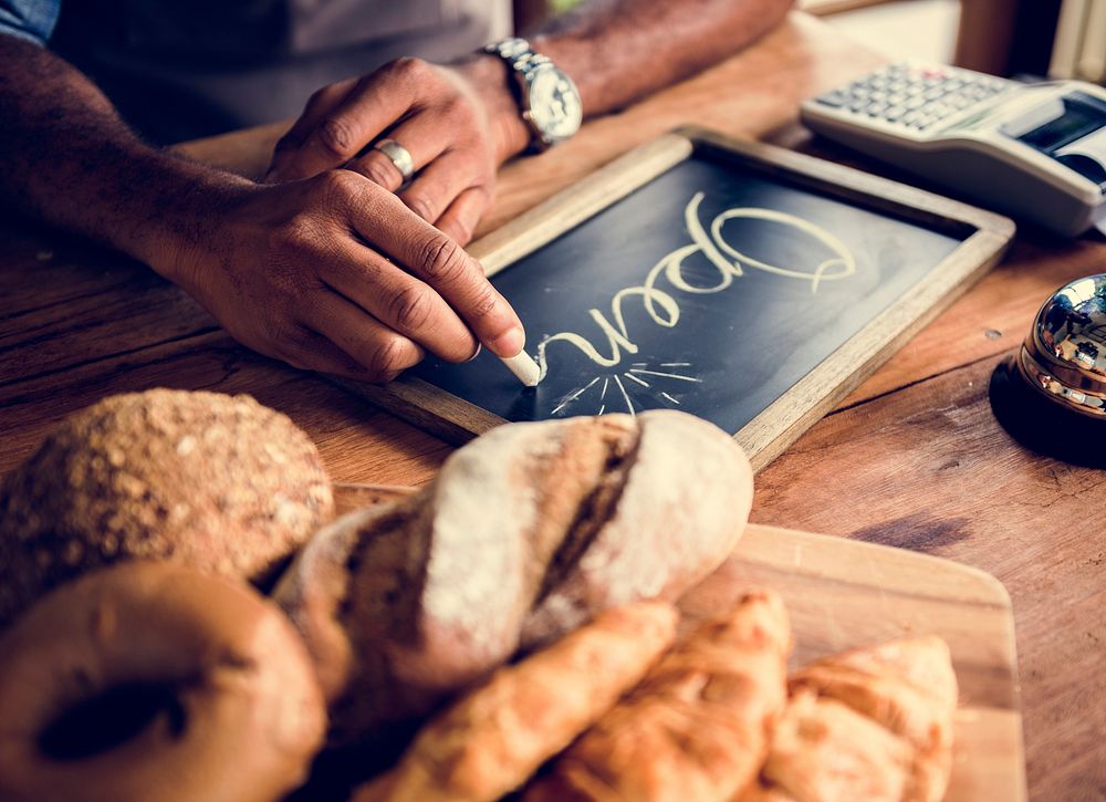 Man writing blackboard about service hour of bakehouse