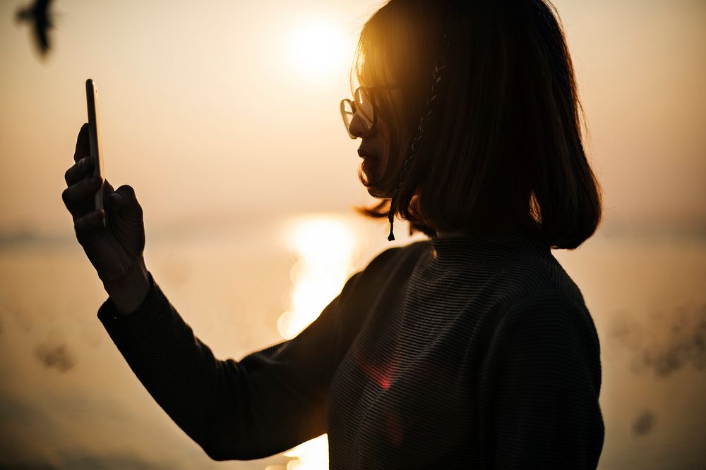 Silhouette of a girl using her mobile phone at sunset