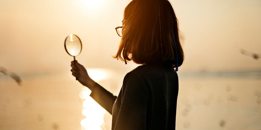 Silhouette of woman holding magnifying glass