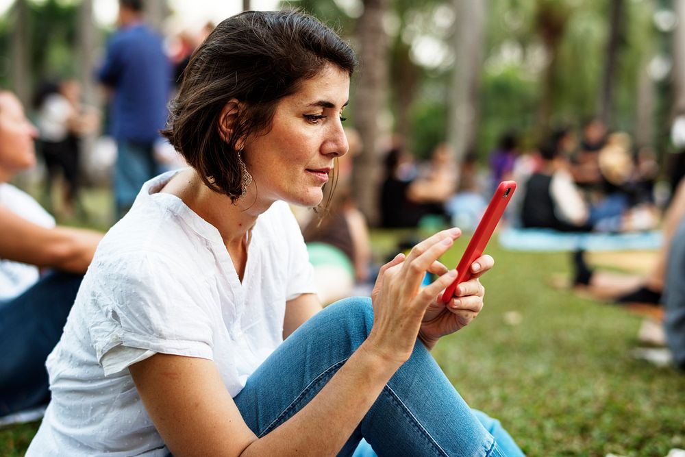 An Adult Woman Sitting in The Park Using Mobile Phone