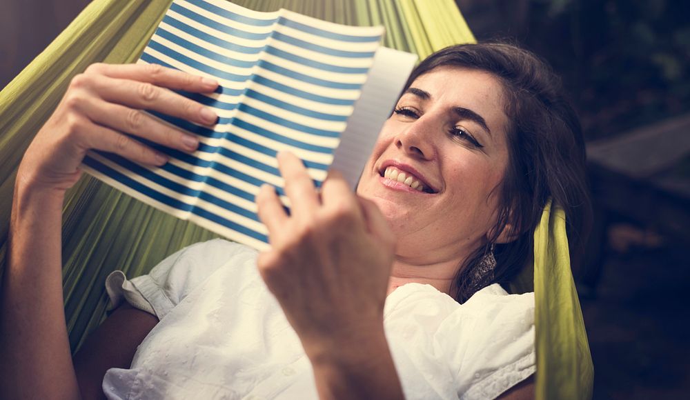 Woman lying on hammock chilling reading book
