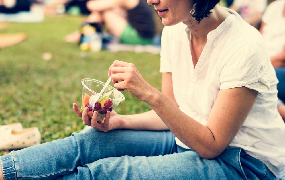 Woman eating fruit picnic at park