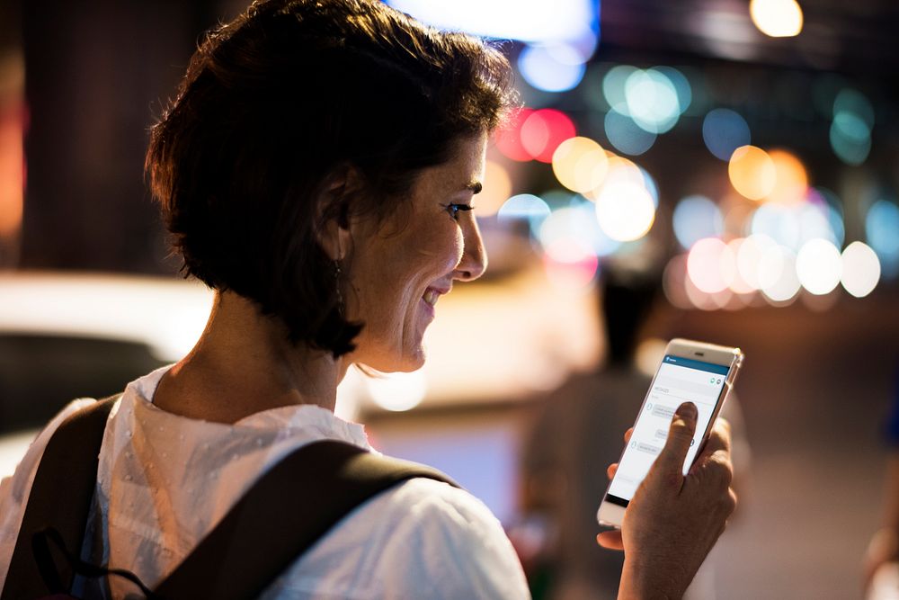Woman using smart phone walking on street night time