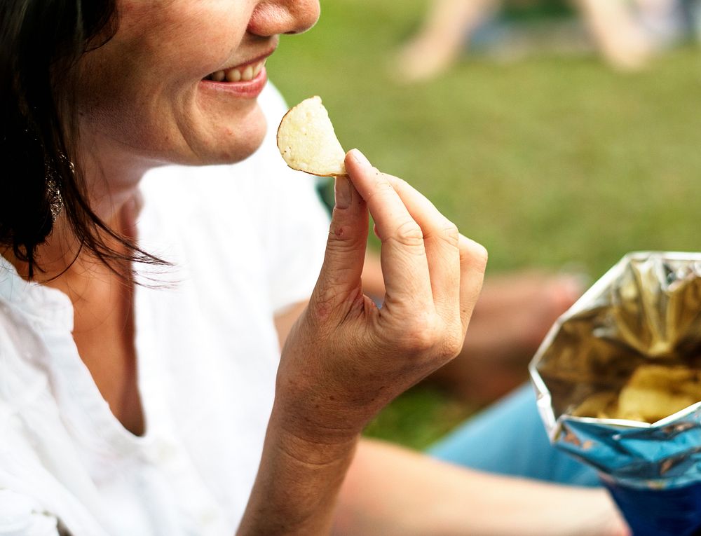 Woman eating potato chip with smiling