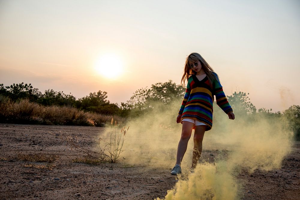 Young woman playing with yellow powder outdoors