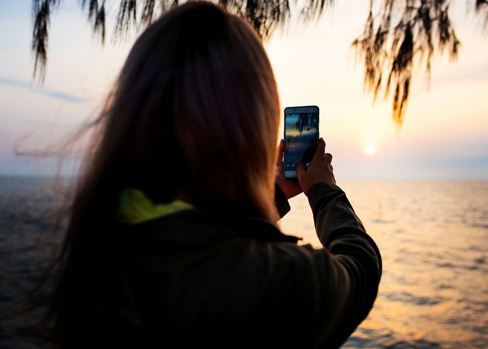 Woman taking a sunset photo on phone camera