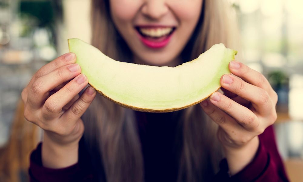 Woman eating melon honeydew with happiness smile