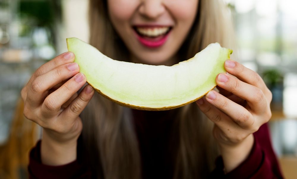 Woman eating melon honeydew with smile