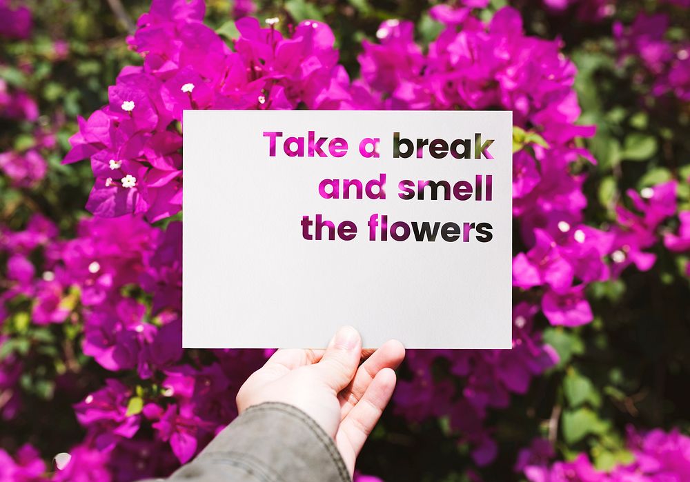 Hand holding paper with take a break and smell the flowers word cut out