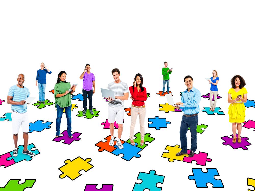 Multi-ethinic people standing on puzzle pieces while social networking via modern technology