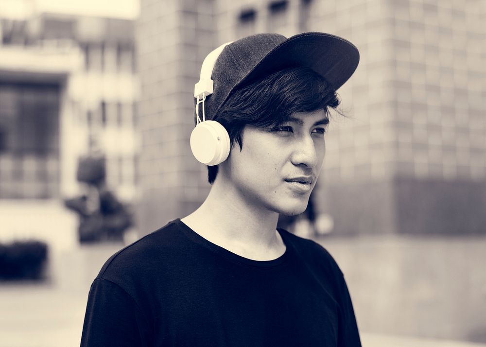 Asian guy listening music by headphones