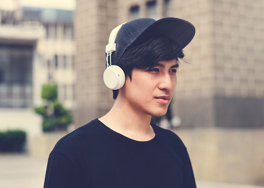 Asian guy listening music by headphones