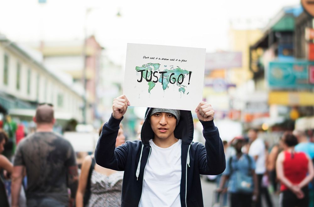 Young asian guy with a Just Go placard