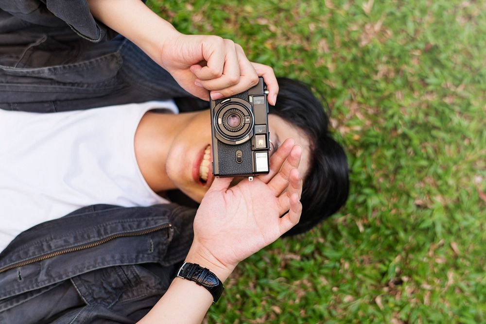 Asian guy lay down and takes photo with camera
