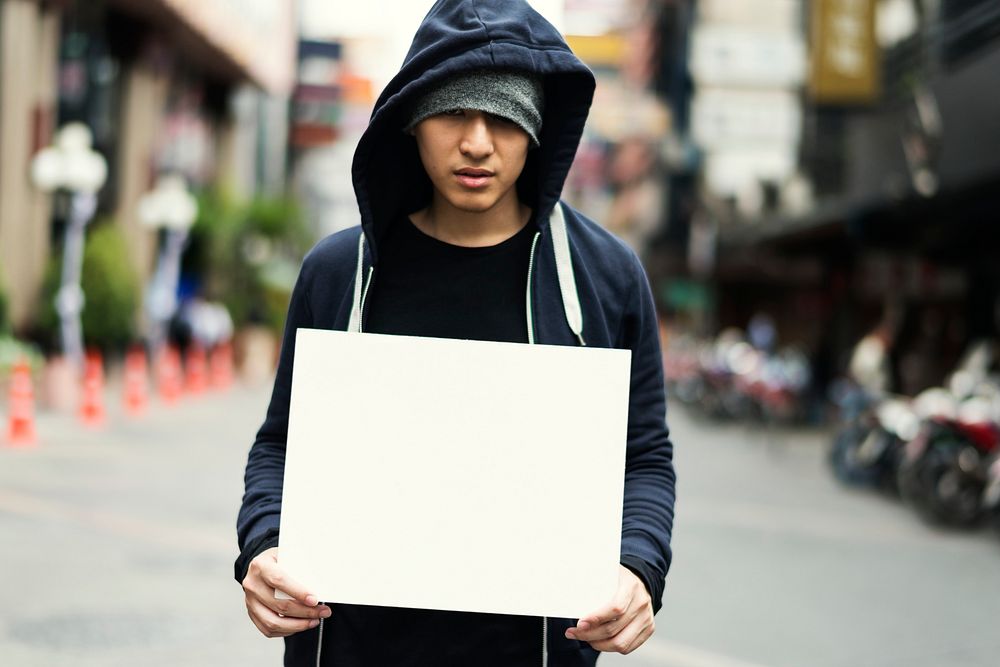 Young asian guy with a blank placard