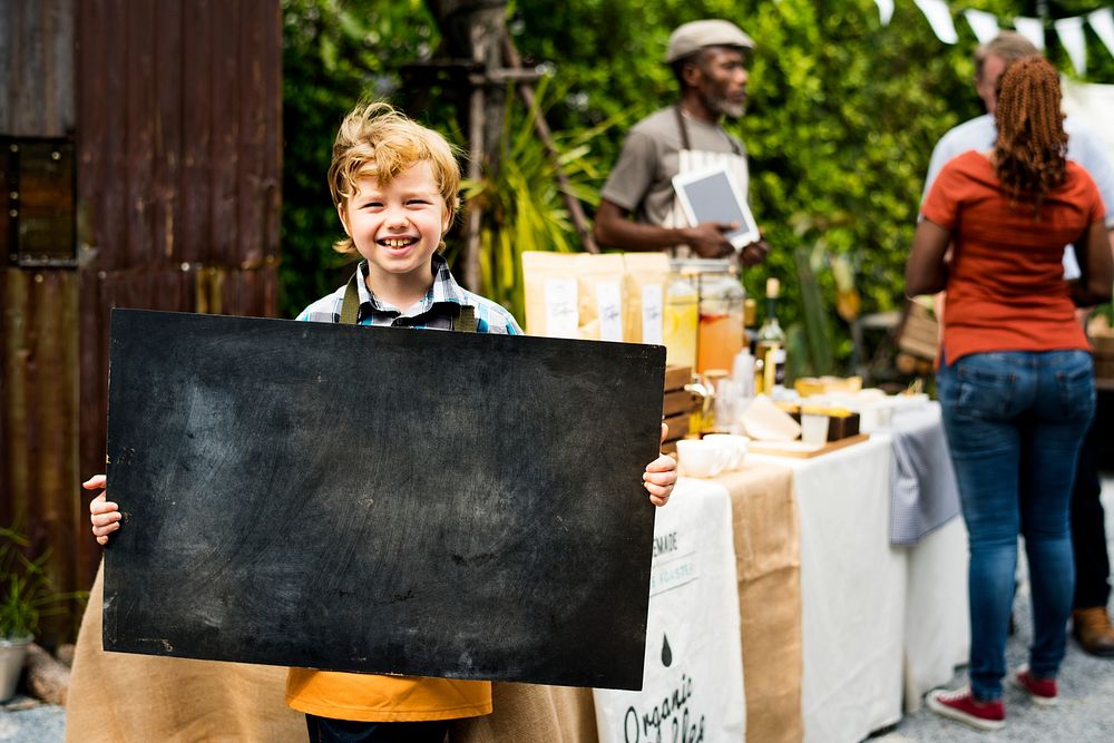 Boy holding copyspace blackboard at farmers market festival