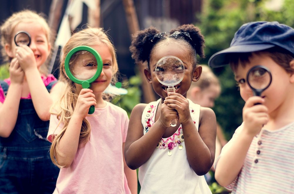Group of kindergarten kids friends holding magnifying glass for