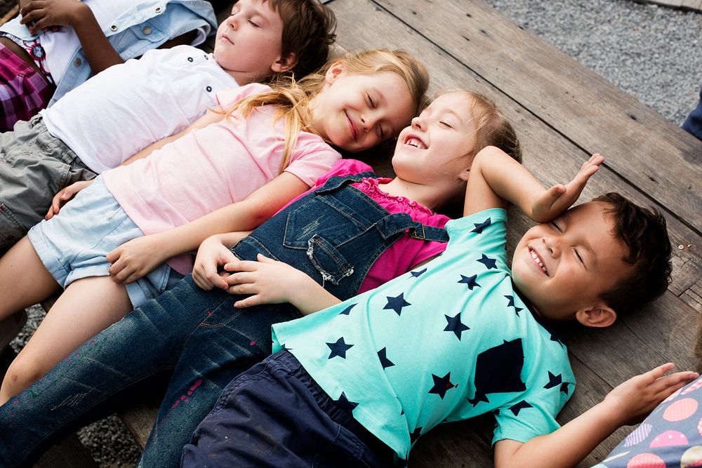 Diverse Little Kids Lay on the Wooden Floor Together