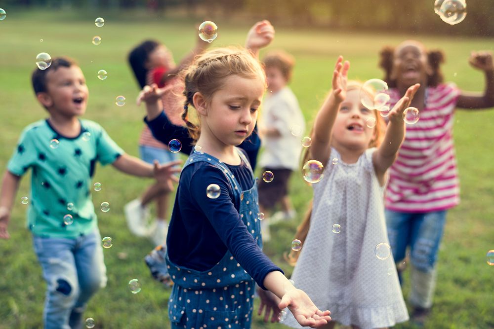 Group of kindergarten kids friends playing blowing bubbles fun
